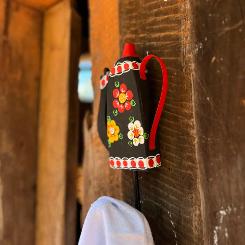 "Um gancho de parede preto segurando um pano de pratos"