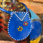 "Detalhes da bolsa azul com flores na escultura de galinha caipira feita de madeira"