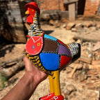 "Uma escultura de galinha caipira amarela com chapeu bolsa e bota com pintura em patchwork"