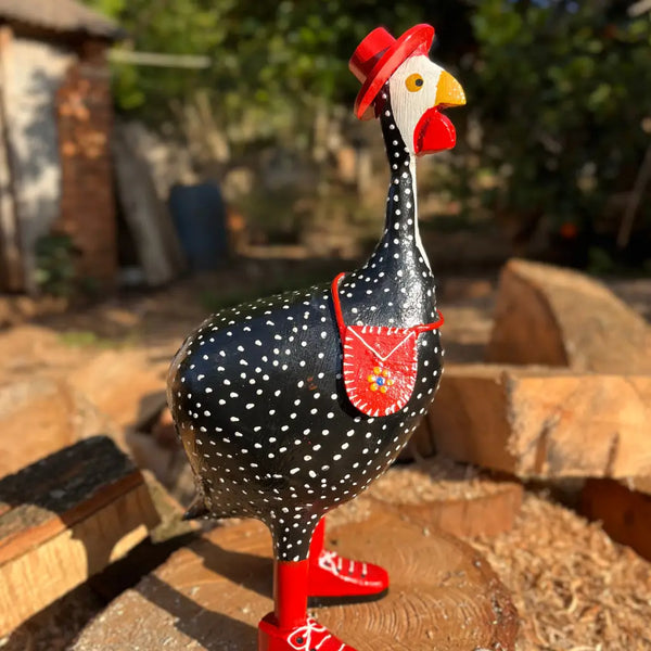 "Uma escultura de galinha d'angola com chapéu bolsa e bota na cor vermelha"