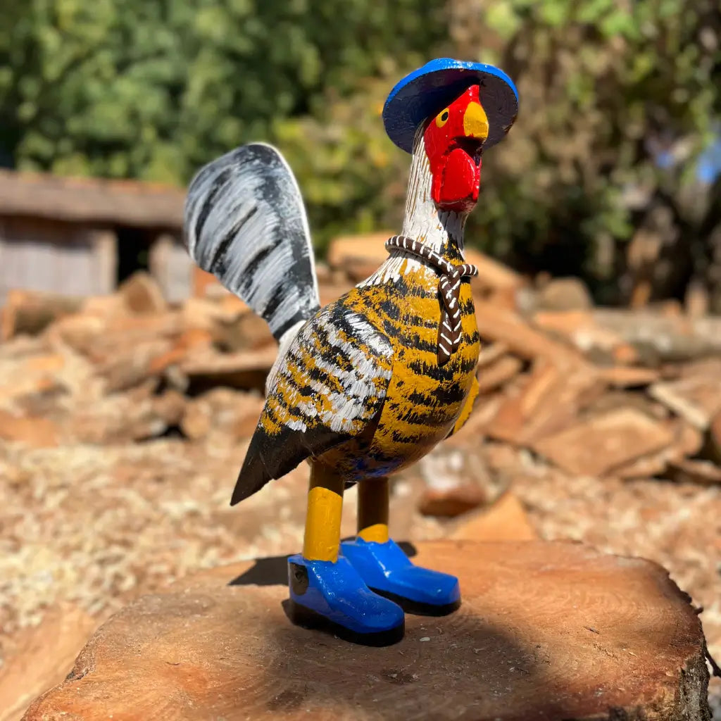 "Uma escultura de madeira de um galo caipira amarelo com chapéu bota e gravata"