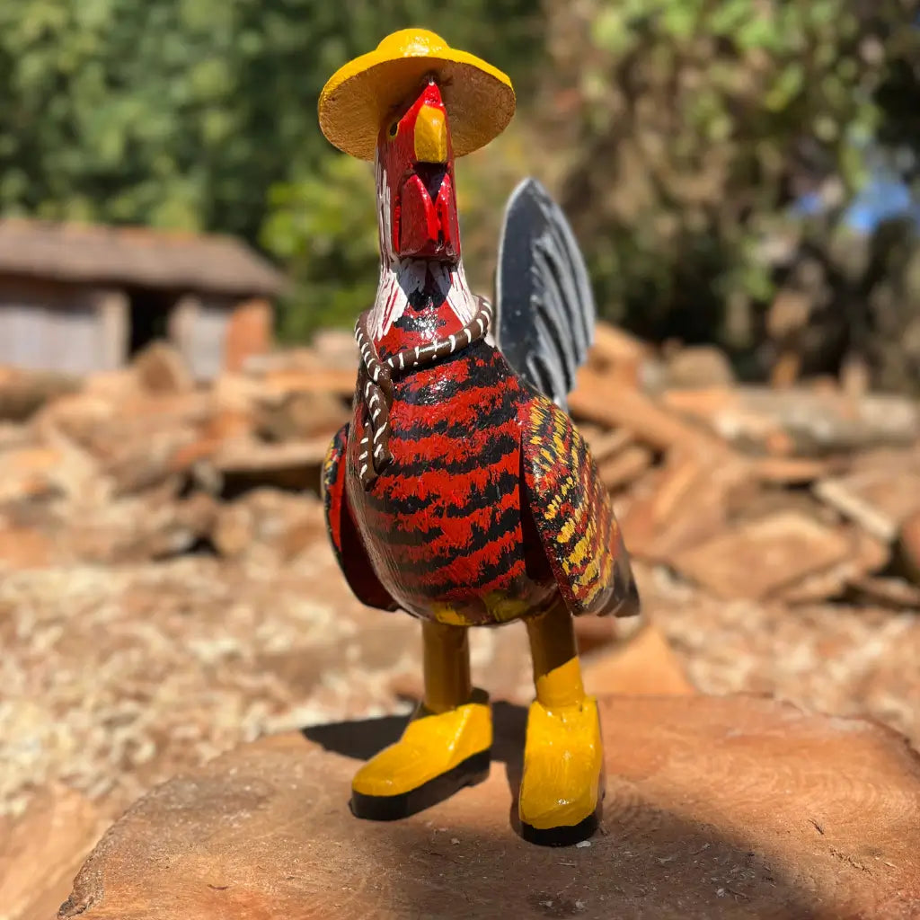 "Uma escultura de madeira de um galo caipira vermelho com chapéu bota e gravata"