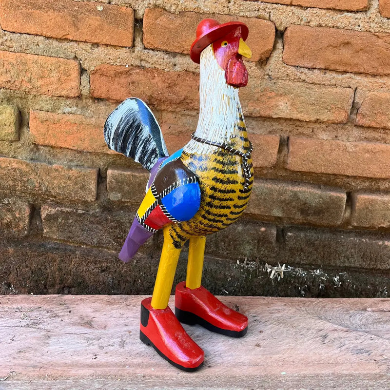 "Uma escultura de galo caipira com bota chapéu e gravata amarelo com pintura patchwork"