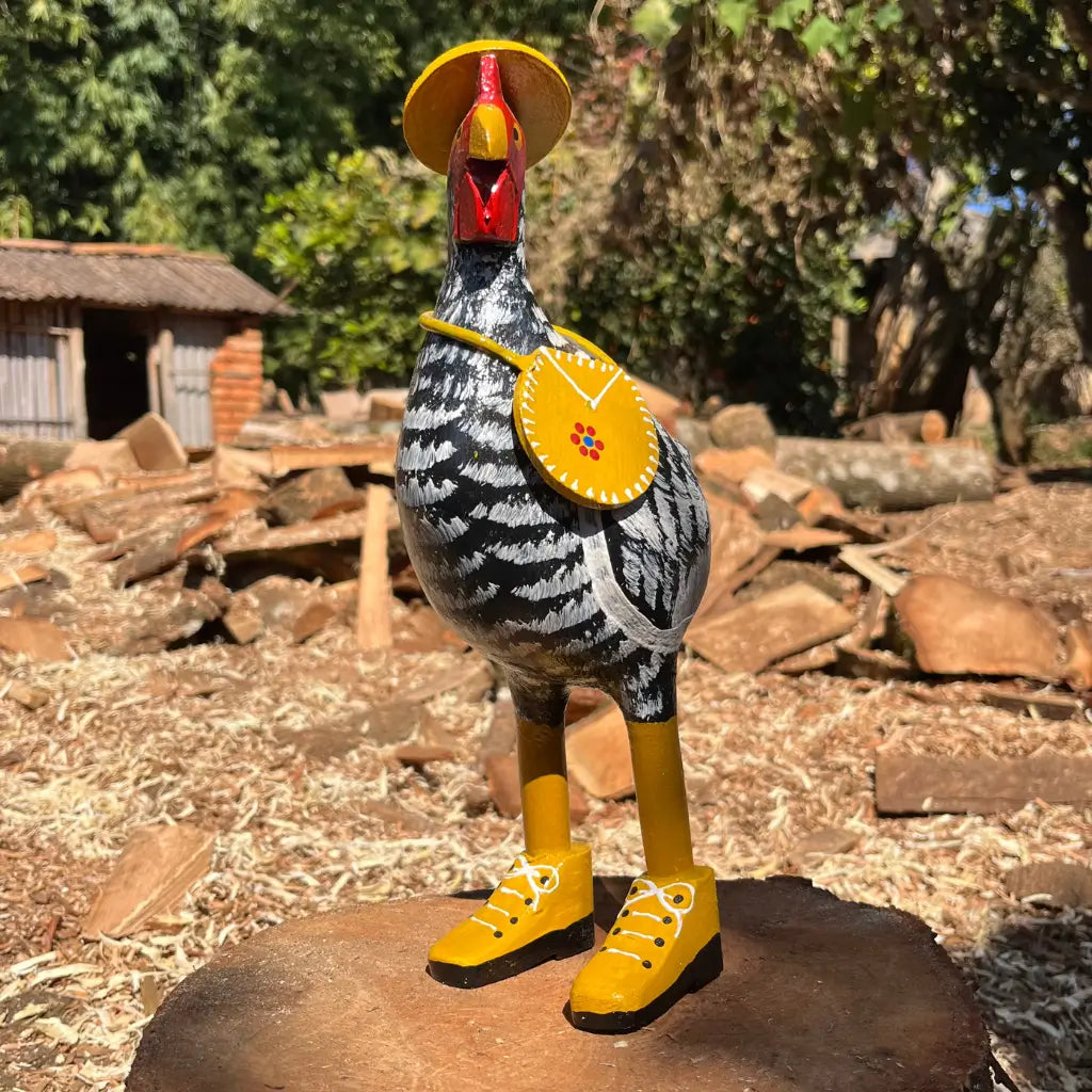 "Uma escultura de madeira de uma galinha caipira de madeira preta com bota chapeu e bolsa"