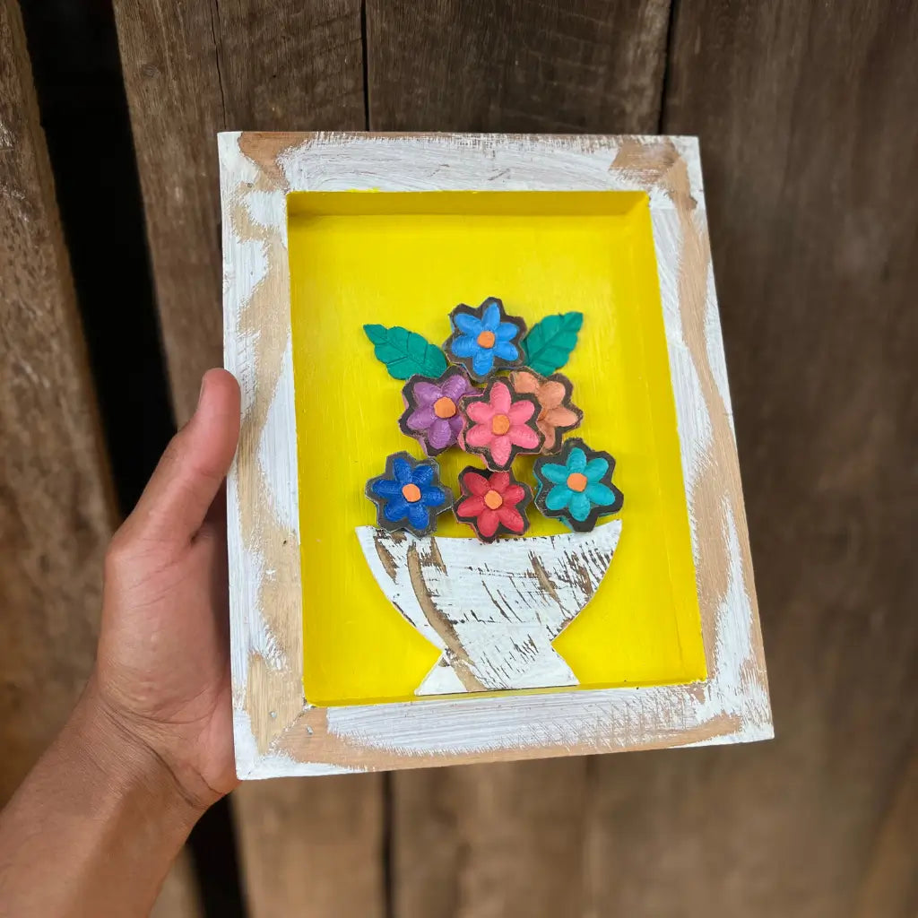 "Um quadro 20 por 25 com vaso de flores sendo segurado nas mãos"