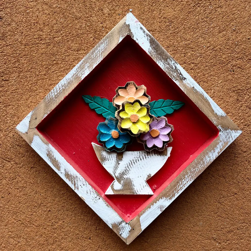 "Um quadro de parede losango em madeira com vaso de flores no fundo vermelho"